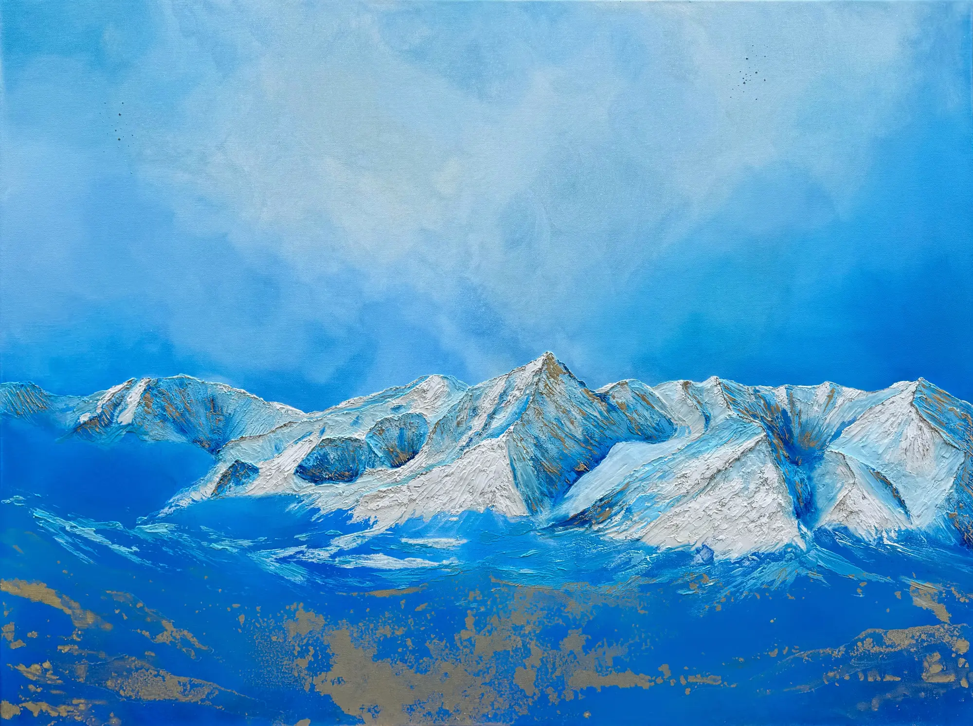 A snow-covered mountain ridge in white and blue under a pale cloudy sky, above deep blue foothills splashed with patches of metallic gold.